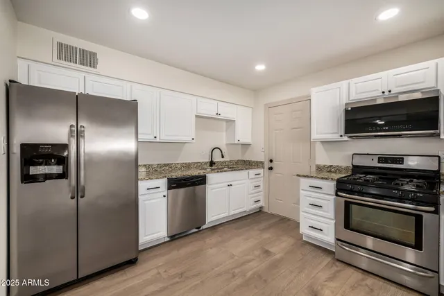 a kitchen with stainless steel appliances granite countertop a refrigerator stove and sink
