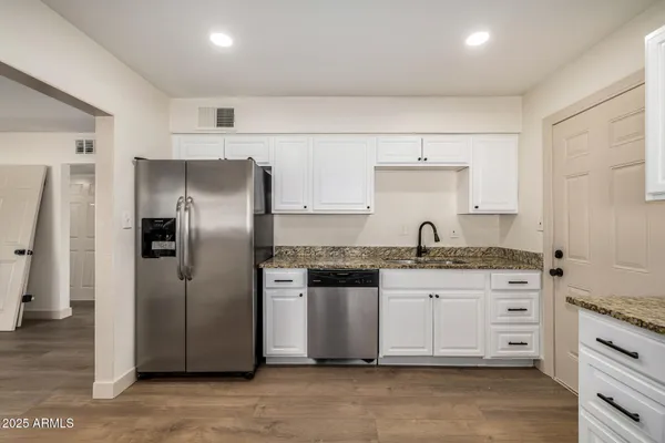 a kitchen with granite countertop a refrigerator stove and sink