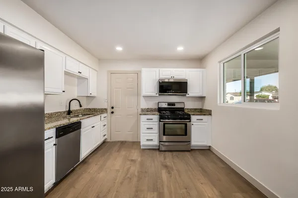 a large kitchen with stainless steel appliances granite countertop a stove and a sink