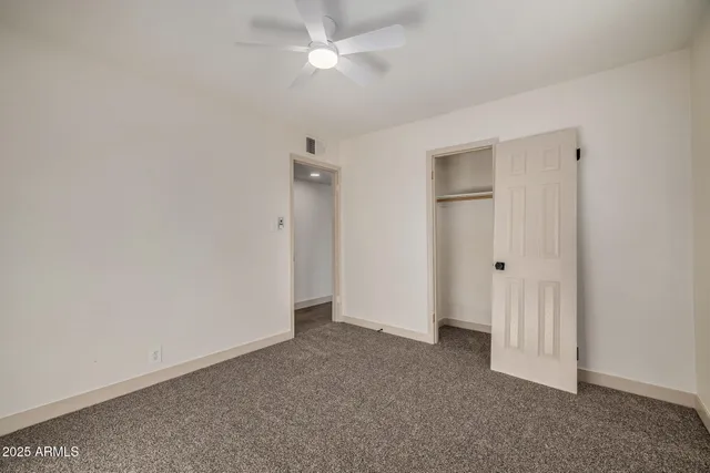 an empty room with a ceiling fan and a window