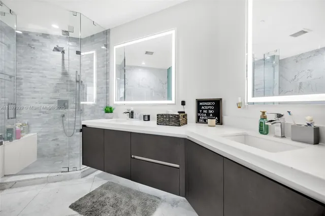 a bathroom with a sink double vanity granite tub shower and a mirror