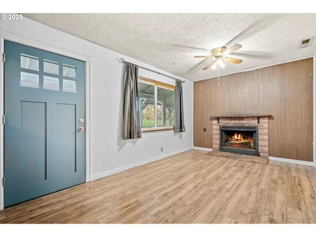 an empty room with windows fireplace and fans