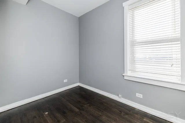 an empty room with wooden floor and a window