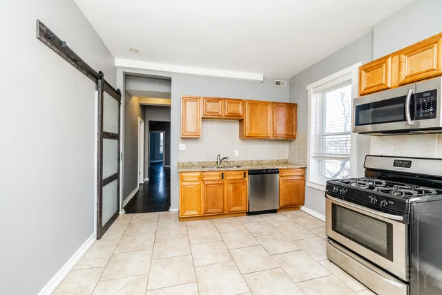 a kitchen with stainless steel appliances granite countertop a stove a sink and a microwave