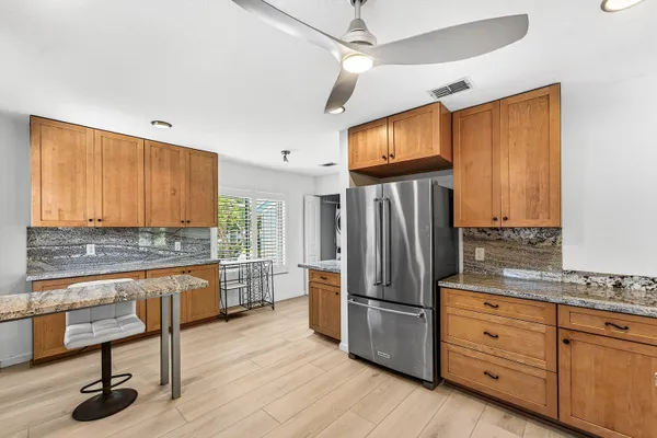a kitchen with granite countertop a stove a sink and a refrigerator
