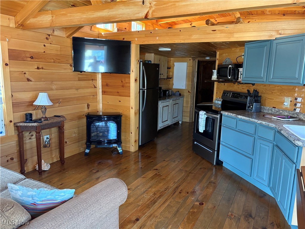 5919 Lake Road West, Unit 13 Ashtabula, OH 44004 - Photo 8 of 35 Kitchen featuring stainless steel electric range oven, a wood stove, blue cabinetry, freestanding refrigerator, and wood walls