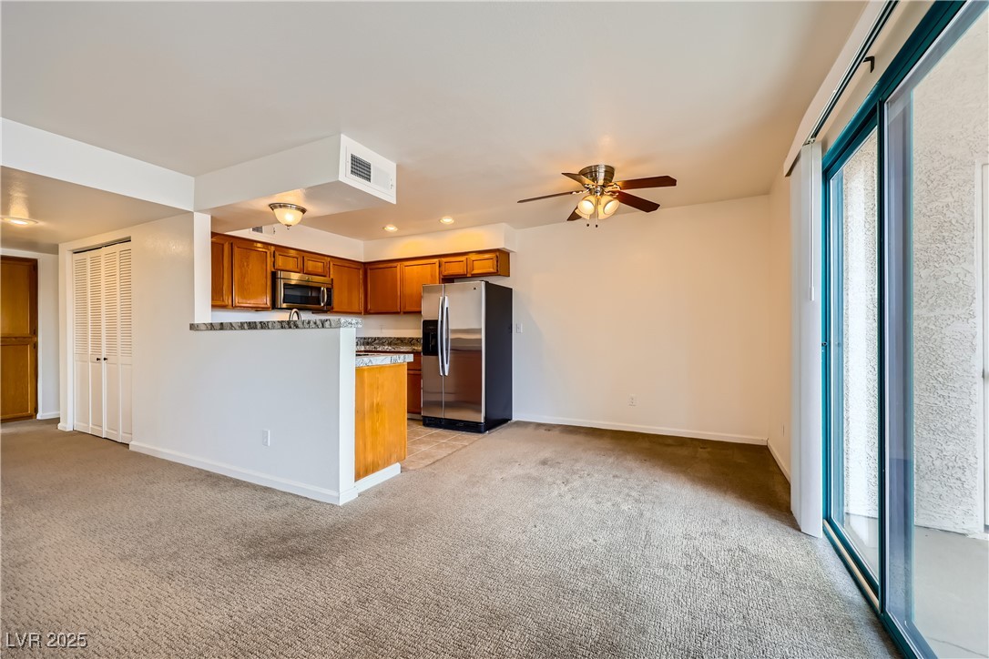 1575 West Warm Springs Road, Unit 1613 Henderson, NV 89014 - Photo 11 of 39 Kitchen with a ceiling fan, light carpet, appliances with stainless steel finishes, brown cabinets, and baseboards