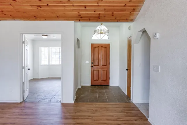 a view of a hallway with wooden floor and a bathroom