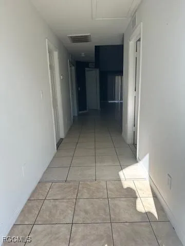 a view of a hallway to an empty room and kitchen