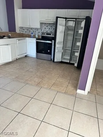 a kitchen with stainless steel appliances granite countertop a stove a sink and white cabinets