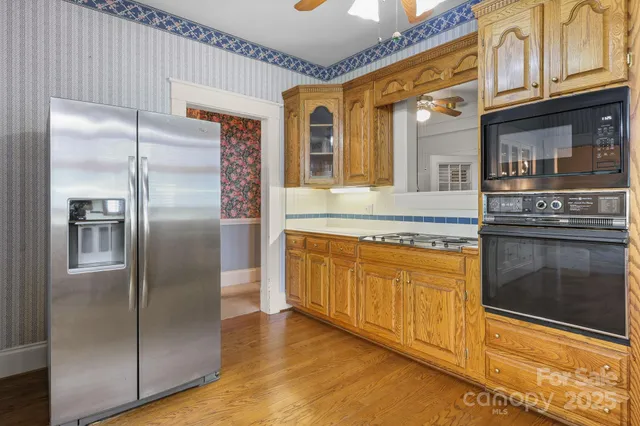a kitchen with stainless steel appliances granite countertop a refrigerator a oven and white cabinets with wooden floors