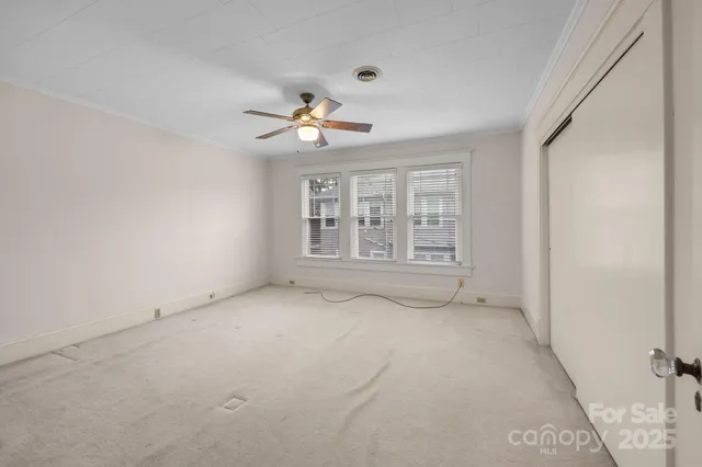 an empty room with windows and ceiling fan