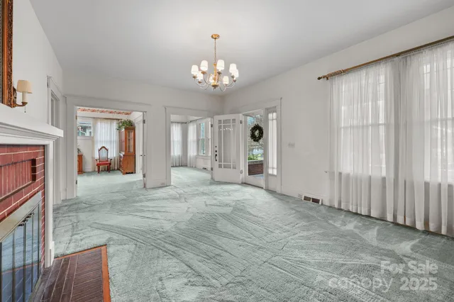an empty room with fireplace chandelier and windows