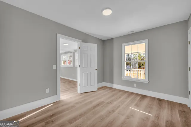 an empty room with wooden floor and windows