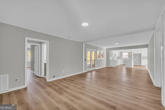 a view of an empty room with wooden floor and window