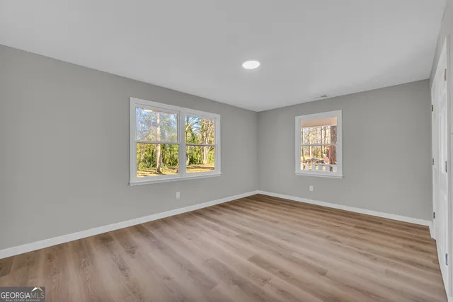 a view of an empty room with a window and wooden floor