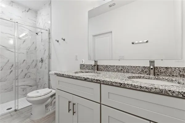 a bathroom with a granite countertop sink a toilet and a shower