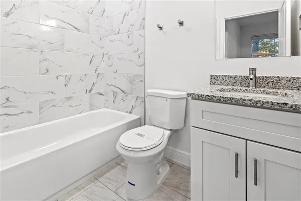 a bathroom with a granite countertop toilet a sink and bathtub