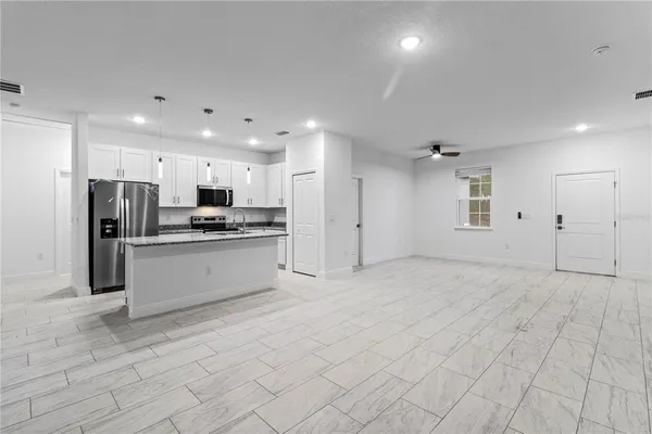 a large white kitchen with a refrigerator a stove top oven and white cabinets
