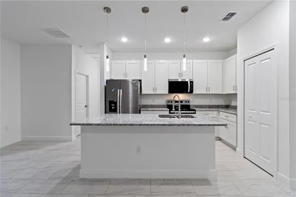 a large kitchen with stainless steel appliances granite countertop a stove a sink and a refrigerator