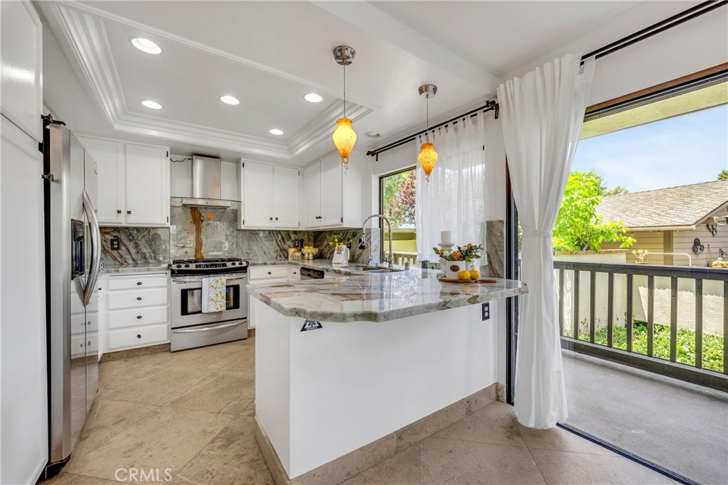 20 Nuevo, Unit 10 Irvine, CA 92612 - Photo 7 of 36 a kitchen with stainless steel appliances kitchen island granite countertop a refrigerator oven a sink dishwasher and white cabinets with wooden floor