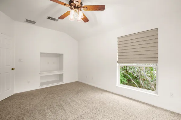 an empty room with windows and fan