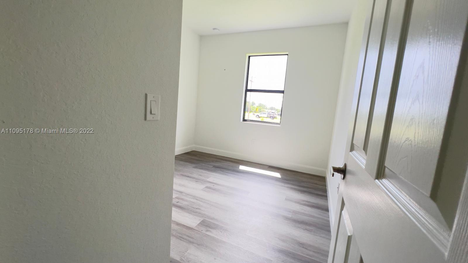 3911 Ordnance Road Lehigh Acres, FL 33971 - Photo 9 of 10 an empty room with wooden floor and windows