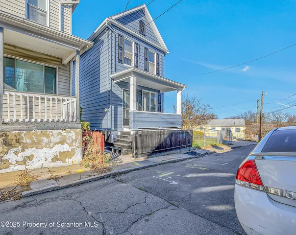 a front view of a house with a yard and potted plants