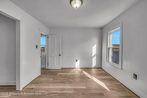 a view of an empty room with window and wooden floor