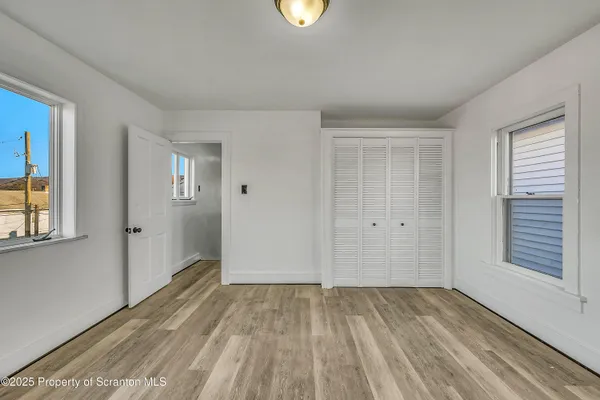 a view of an empty room with closet and a window