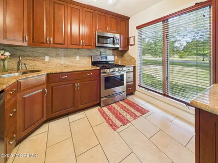 a kitchen with stainless steel appliances granite countertop a stove top oven a sink dishwasher and a microwave oven on the granite countertops