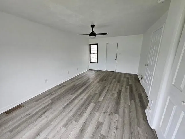 a view of a room with wooden floor a ceiling fan and window