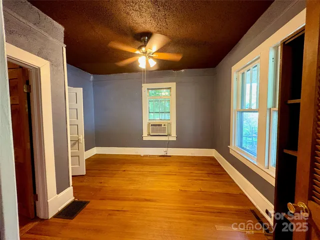 a view of an empty room with window and wooden floor
