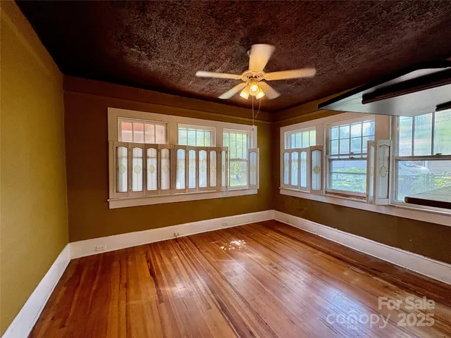a view of an empty room with wooden floor and a window