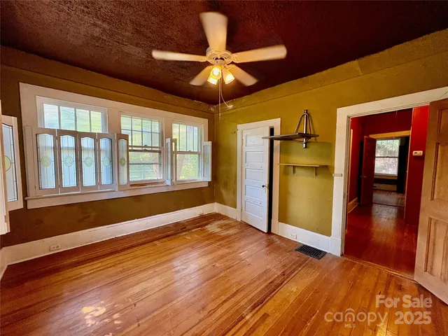 a view of an empty room with window and wooden floor