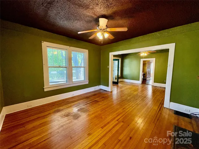 a view of an empty room with window and wooden floor