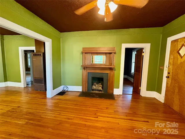 a view of a livingroom with wooden floor and a fireplace