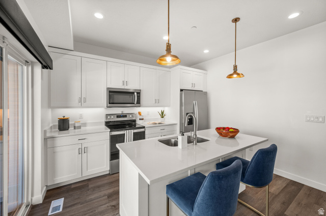 12241 900 East, Unit 7 Draper, UT 84020 - Photo 6 of 22 Modern kitchen featuring white cabinetry, stone countertops, stainless steel appliances, a center island with an integrated sink, and wood-finish flooring