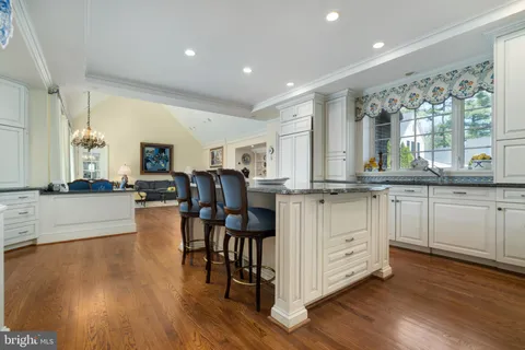 a kitchen with stainless steel appliances granite countertop a stove a sink dishwasher and a dining table with wooden floor