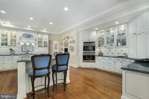 a kitchen with stainless steel appliances granite countertop a stove top oven a sink a dining table and chairs with wooden floor