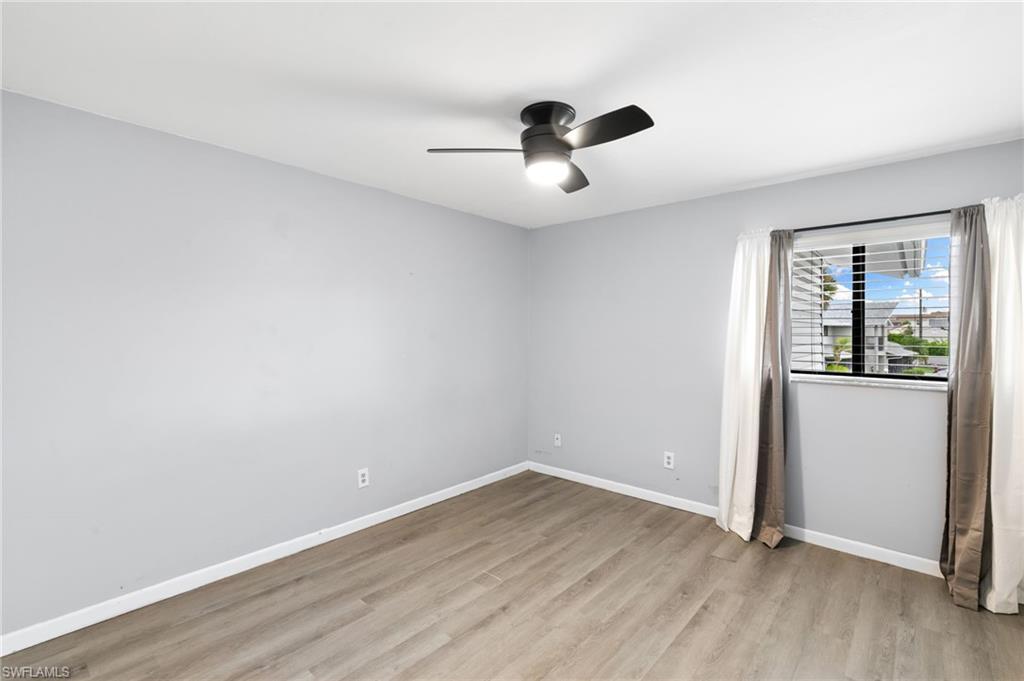 17017 Golfside Circle, Unit 404 Fort Myers, FL 33908 - Photo 13 of 22 an empty room with wooden floor and windows