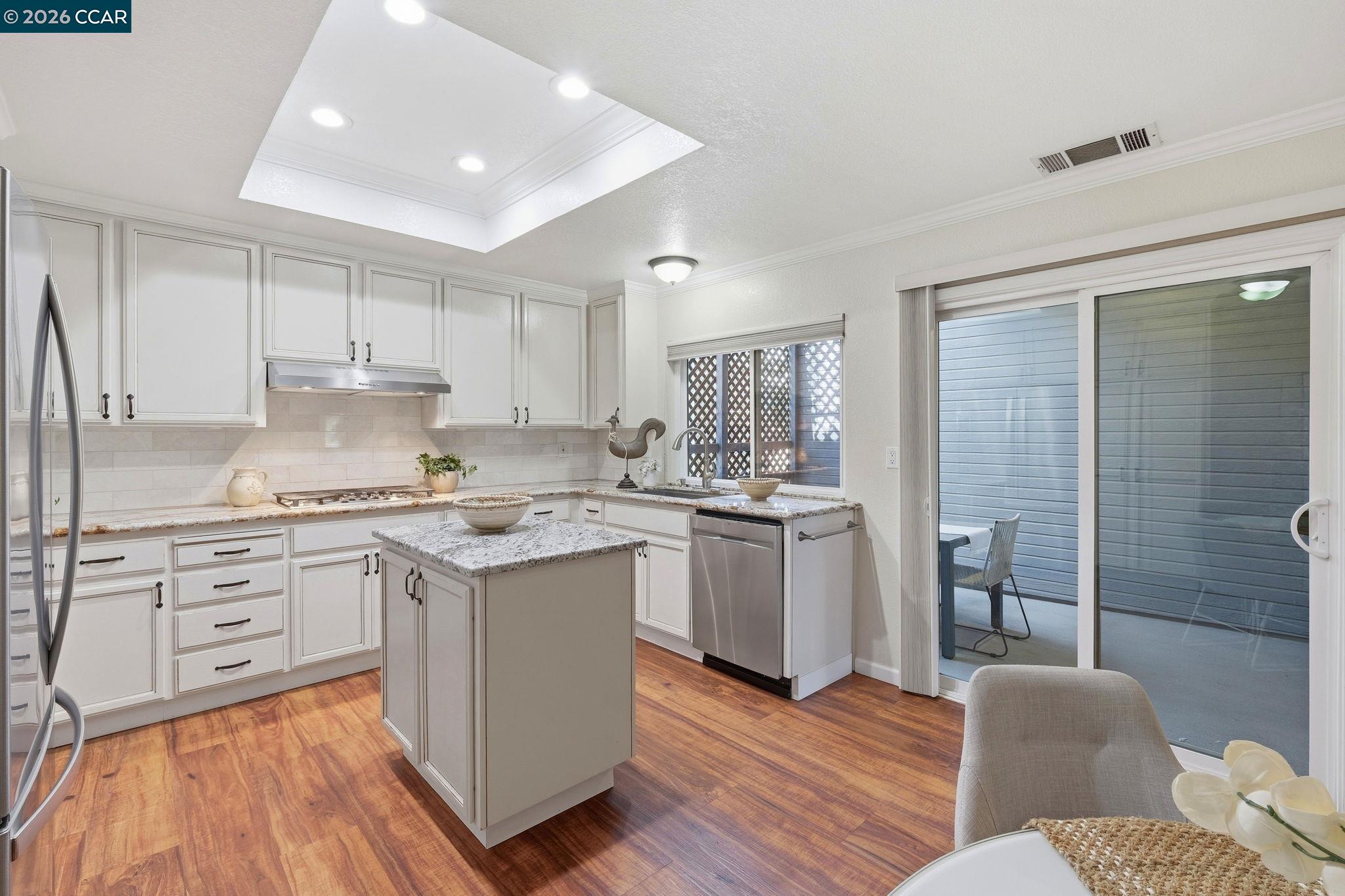 1707 Geary Road Walnut Creek, CA 94597 - Photo 11 of 43 a kitchen with kitchen island granite countertop a sink cabinets and wooden floor