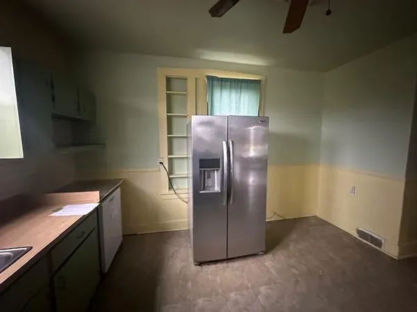a view of a refrigerator in kitchen and an empty room
