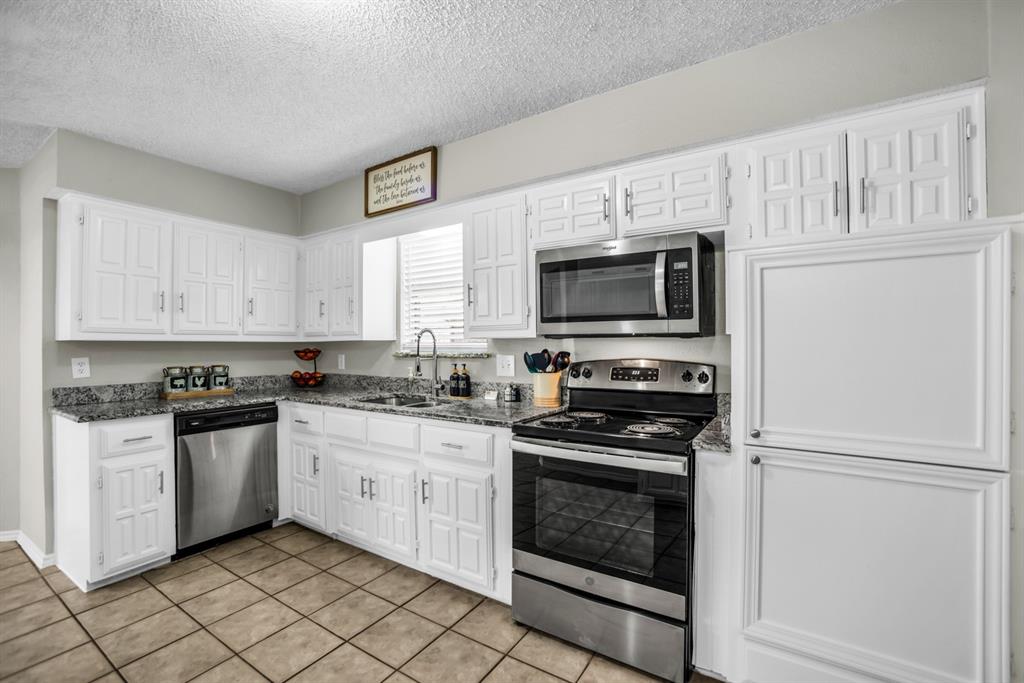 5902 Fawn Valley Lane Rowlett, TX 75089 - Photo 12 of 27 a kitchen with granite countertop white cabinets stainless steel appliances and a sink