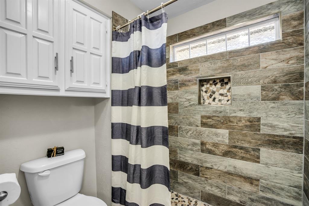 5902 Fawn Valley Lane Rowlett, TX 75089 - Photo 17 of 27 a bathroom with a toilet and a shower curtain