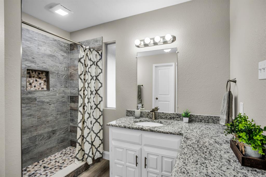 5902 Fawn Valley Lane Rowlett, TX 75089 - Photo 22 of 27 a bathroom with a granite countertop sink a mirror and a shower