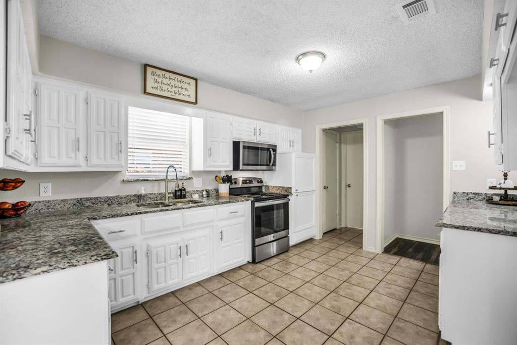 5902 Fawn Valley Lane Rowlett, TX 75089 - Photo 10 of 27 a kitchen with granite countertop a sink stove refrigerator and cabinets