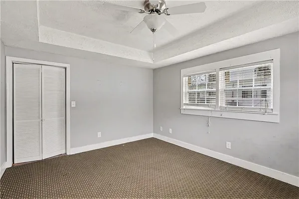 an empty room with a ceiling fan and windows