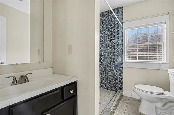 a bathroom with a granite countertop sink a toilet a mirror and shower