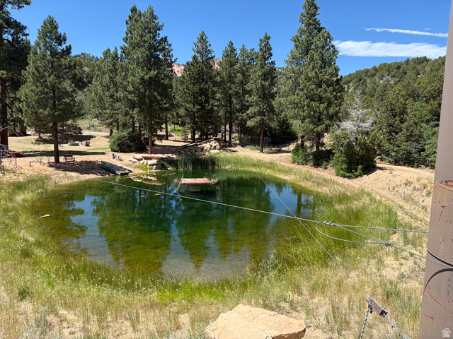 700 West Gravel Road North Kanab, UT 84741 - Photo 45 of 63 Expansive natural pond with lush surrounding foliage and mature trees, set against a backdrop of rolling hills